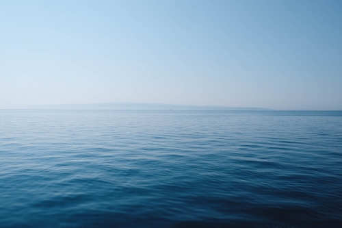 Photo taken out in an ocean in the morning with small waves and a blue and pink sky